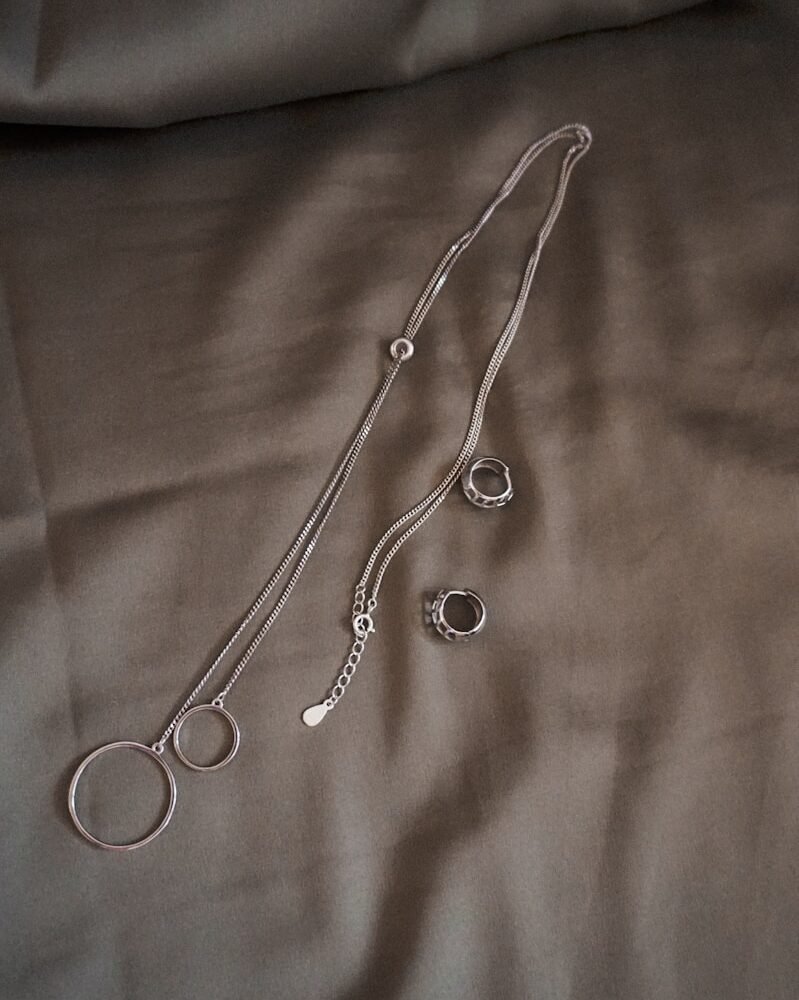 silver necklace on white textile