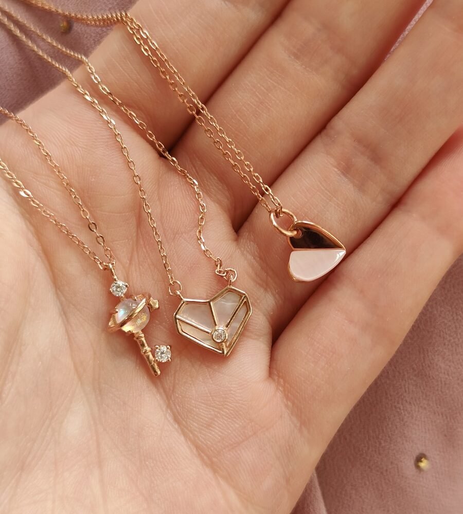 a woman's hand holding four different necklaces
